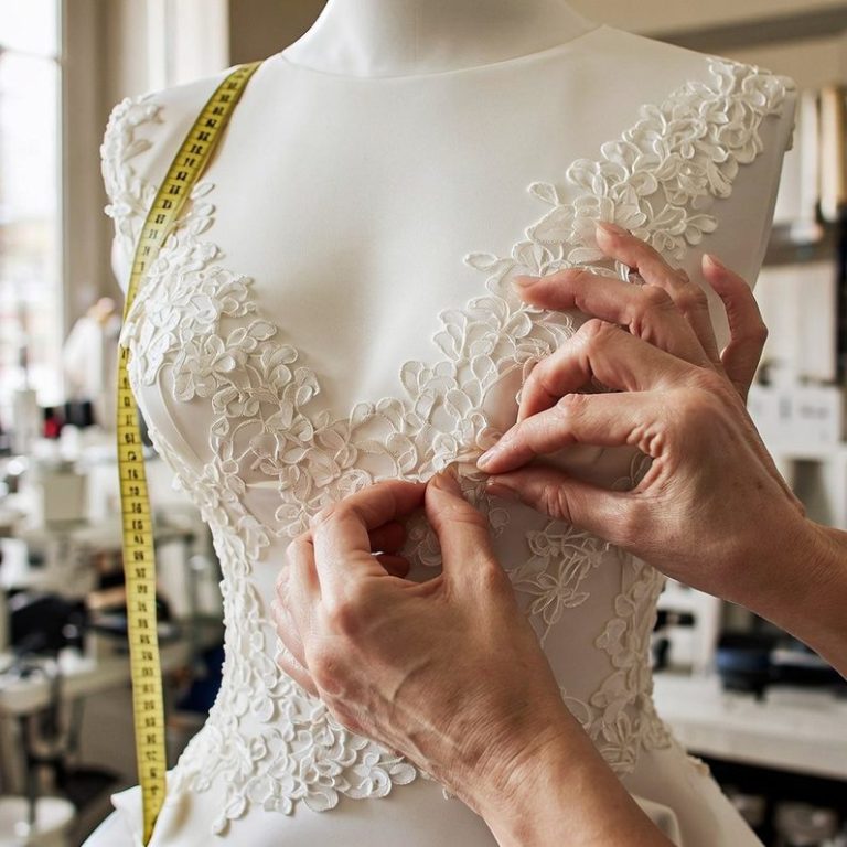 vestido de novia Manos ajustando delicadamente un vestido de novia con bordado en un taller de costura.