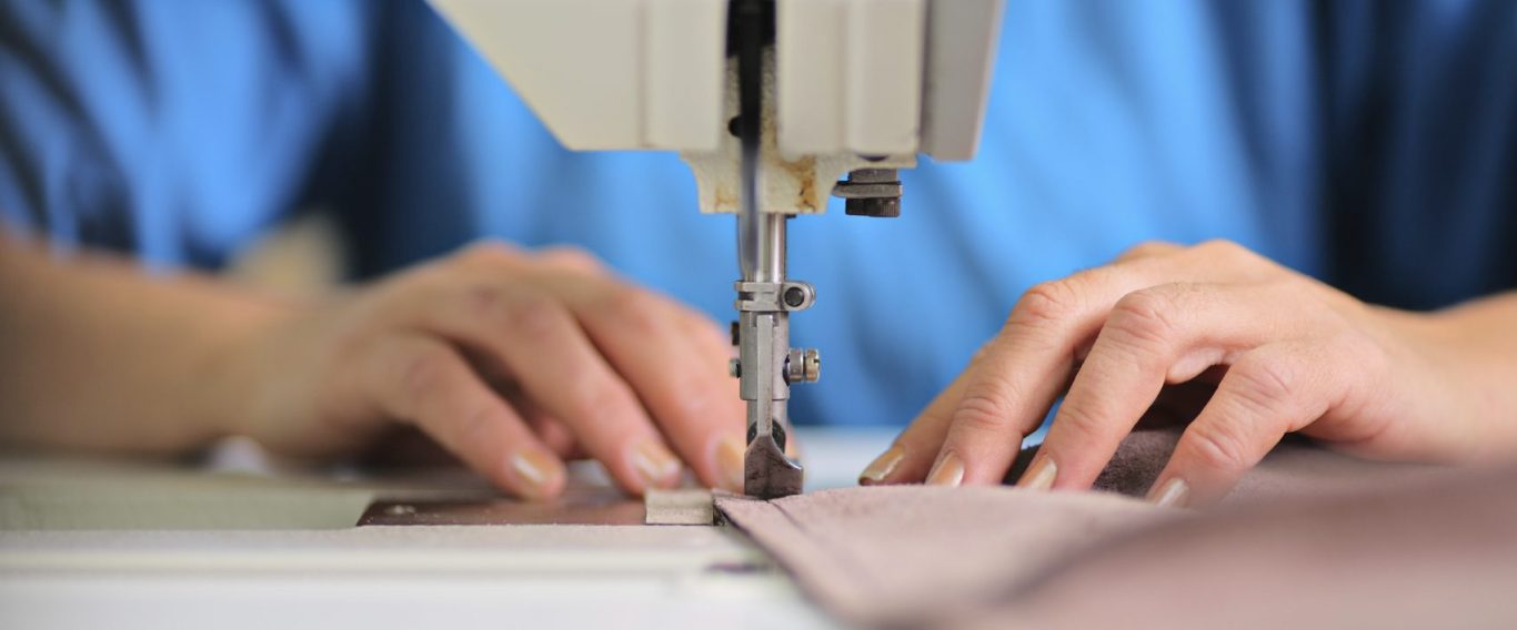 Mujer cosiendo a maquina cosiendo un bajo de pantalón en maquina de coser