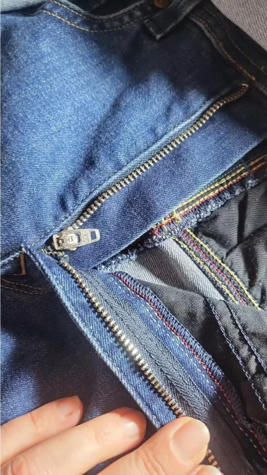 Reparación de Cremallera en Pantalón Vaquero Modista Rosa cosiendo una nueva cremallera en un pantalón vaquero (jean) azul. Servicio de reparación de cremalleras en Rafelbunyol.