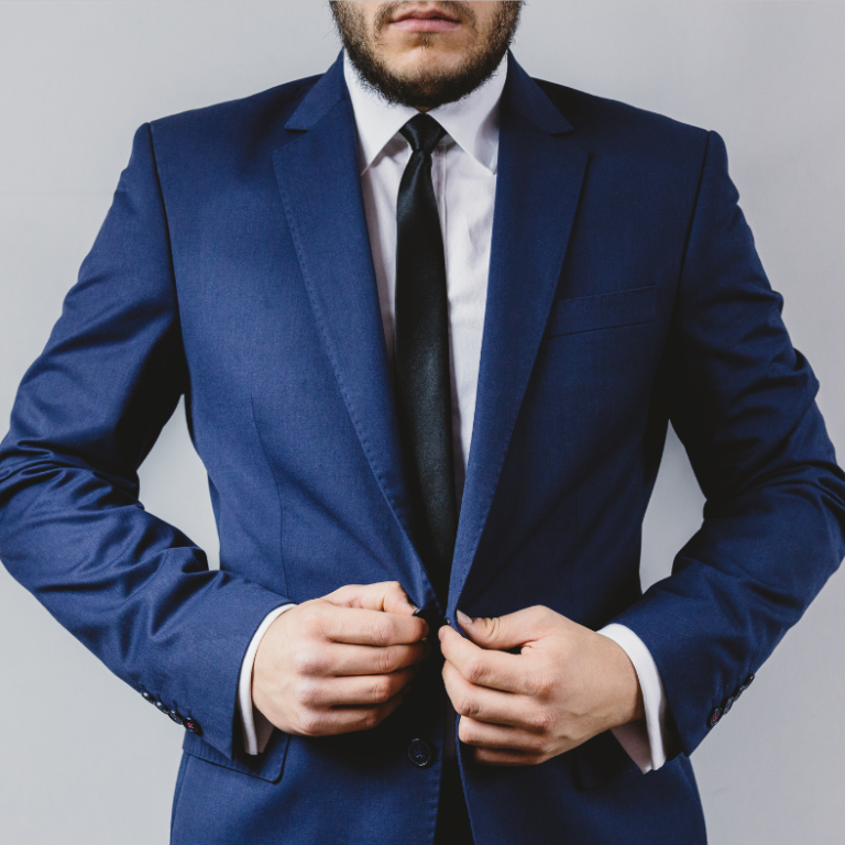 americana Hombre ajustando el saco de un traje azul con una corbata negra.