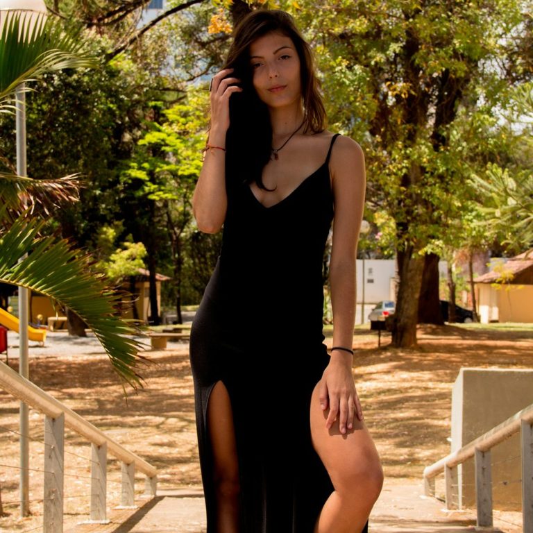 mujer con vestido negro Mujer joven con vestido negro, posando en un entorno natural con árboles.